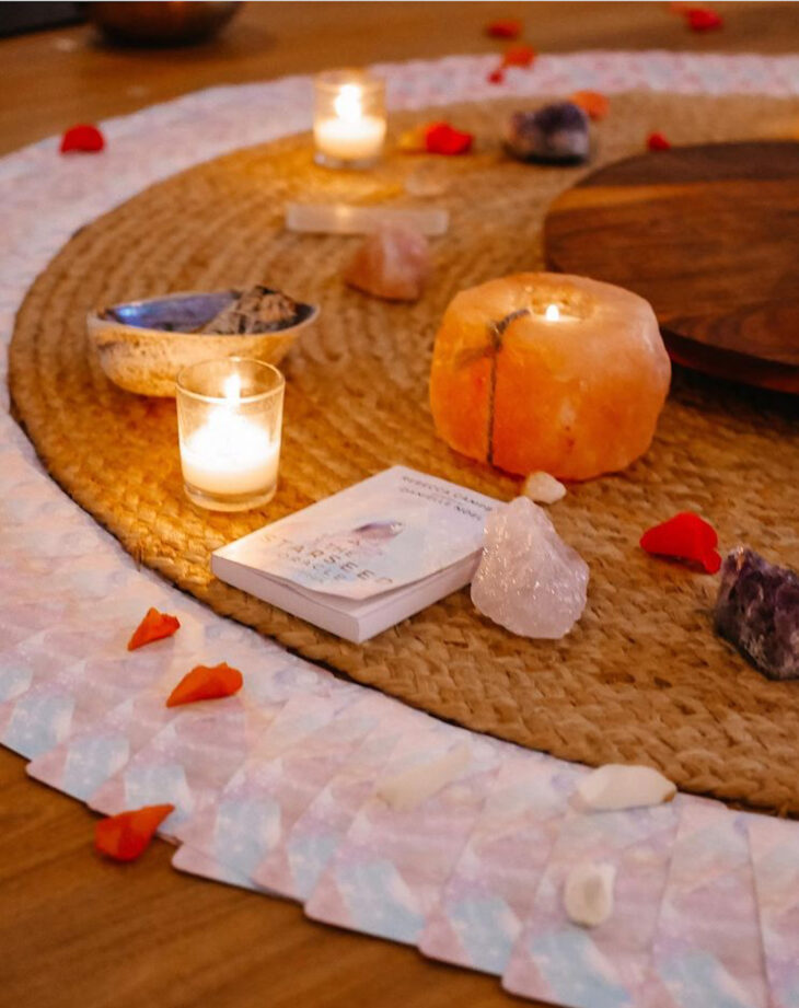 Central circle with salt lamp and cards, rose petals on a woven mat