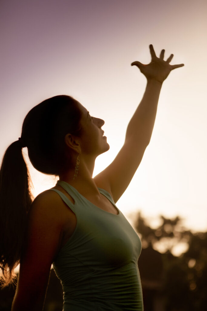 Silhouette of woman with arm outstretched to the morning sun