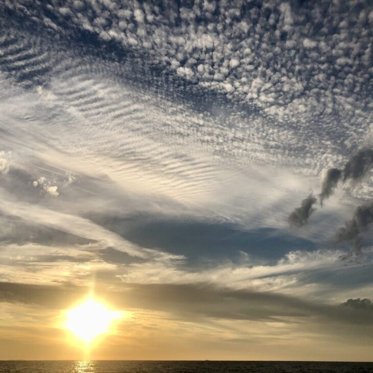 sunsets over the ocean with patterned clouds